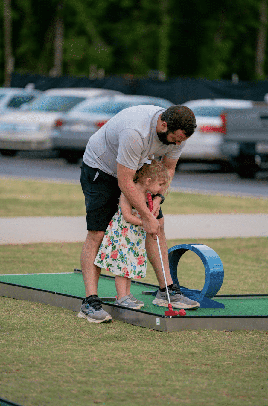 Dad showing daughter how to play mobile mini golf 